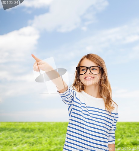 Image of cute little girl in eyeglasses pointing in the air