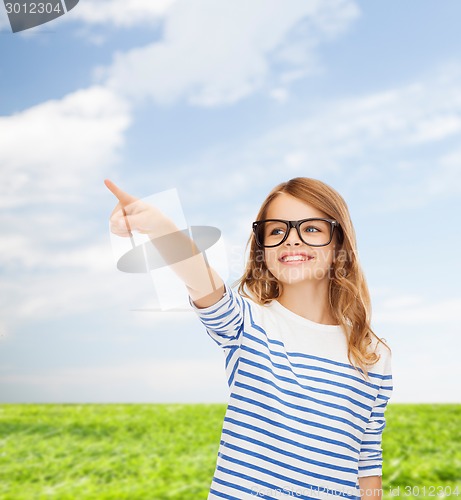 Image of cute little girl in eyeglasses pointing in the air