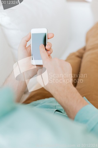 Image of close up of man sitting with smartphone at home