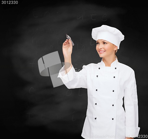 Image of smiling female chef writing something on air