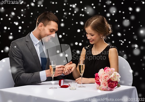 Image of smiling couple with red gift box at restaurant