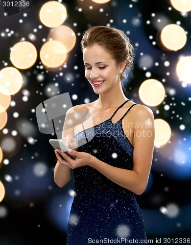 Image of smiling woman in evening dress with smartphone