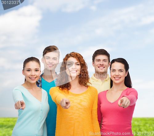 Image of group of smiling teenagers over blue sky and grass