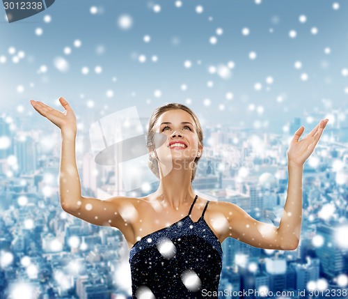 Image of smiling woman raising hands and looking up