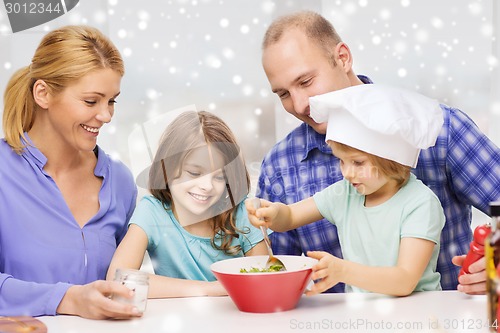 Image of happy family with two kids making salad at home