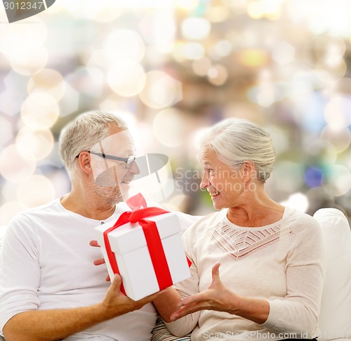 Image of happy senior couple with gift box at home