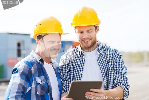 Image of smiling builders in hardhats with tablet pc