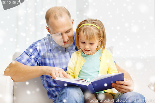 Image of smiling father and daughter with book at home