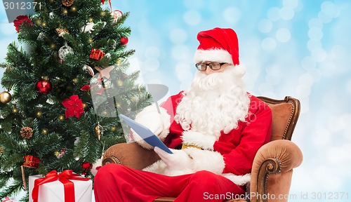 Image of man in costume of santa claus with tablet pc