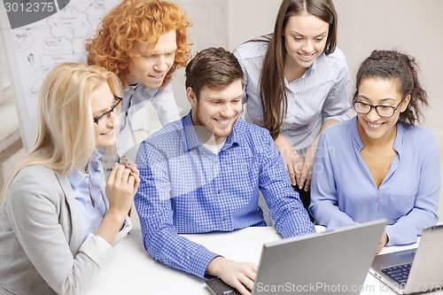 Image of smiling team with laptop computers in office