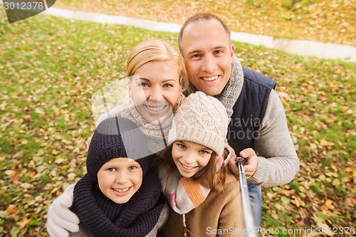 Image of happy family with selfie stick in autumn park