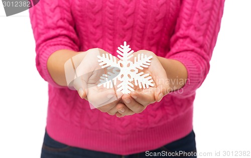 Image of close up of woman in sweater holding snowflake