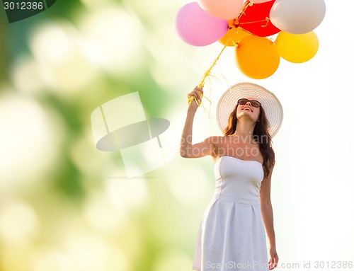 Image of smiling young woman in sunglasses with balloons