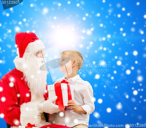 Image of smiling little boy with santa claus and gifts