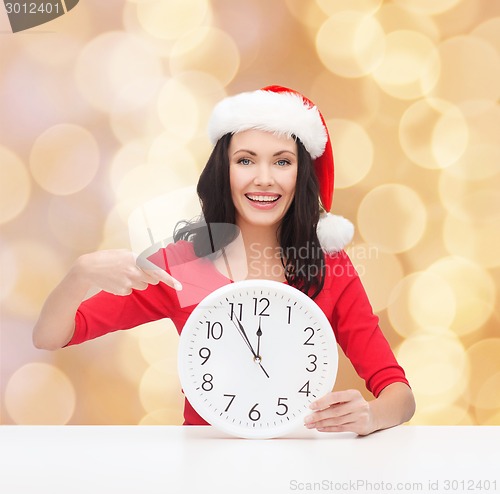 Image of smiling woman in santa helper hat with clock