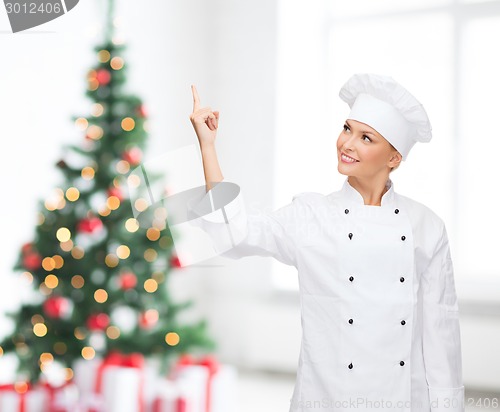 Image of smiling female chef pointing finger to something