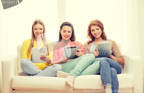 Image of three smiling teenage girls with tablet pc at home