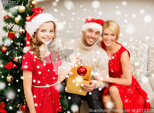 Image of smiling family decorating christmas tree at home