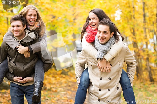 Image of smiling friends having fun in autumn park