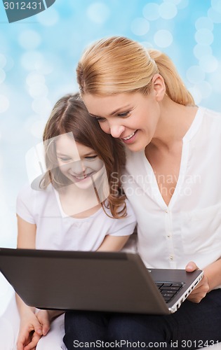 Image of smiling mother and little girl with laptop