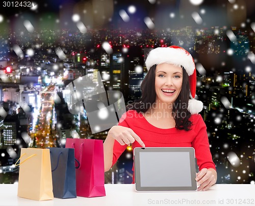 Image of smiling woman in santa hat with bags and tablet pc