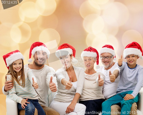 Image of happy family in santa hats showing thumbs up