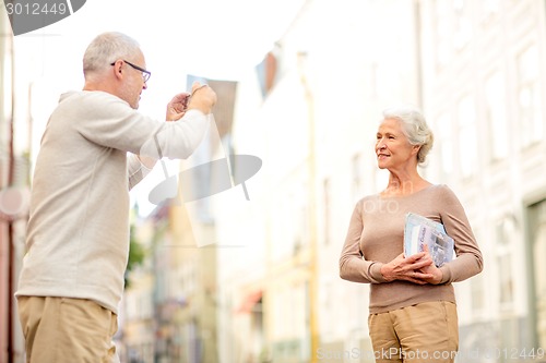 Image of senior couple photographing on city street