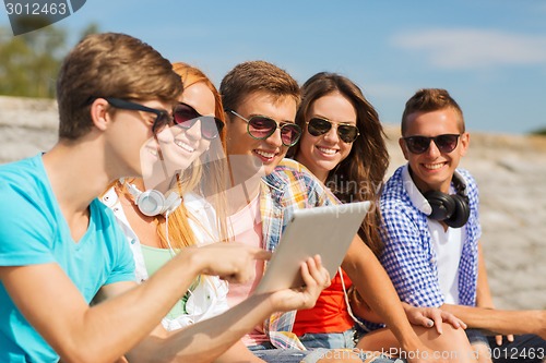 Image of group of smiling friends with tablet pc outdoors