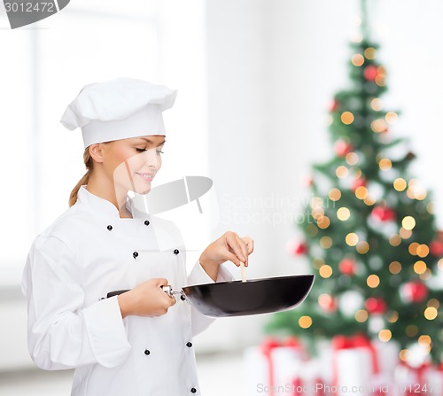 Image of smiling female chef with pan and spoon