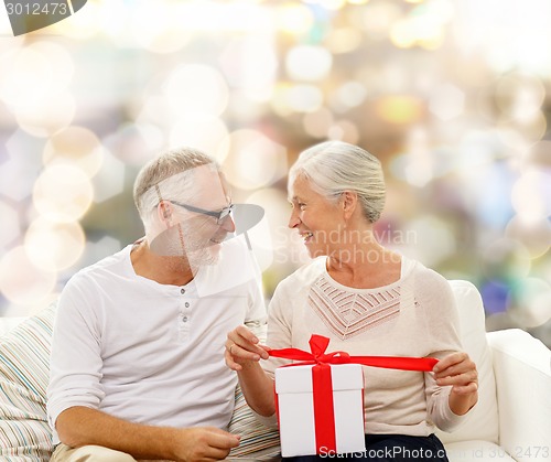 Image of happy senior couple with gift box at home