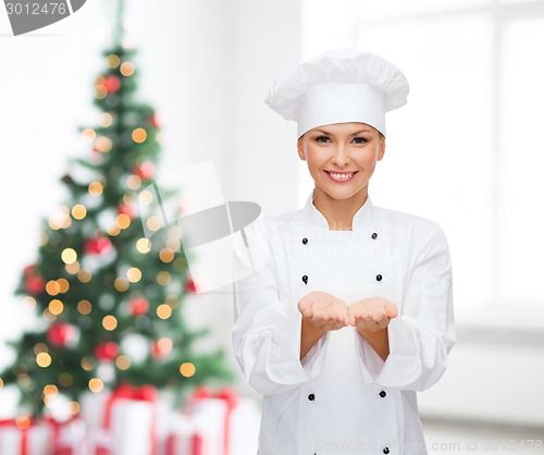 Image of smiling female chef holding something on hands