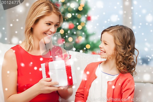 Image of smiling mother and daughter with gift box at home