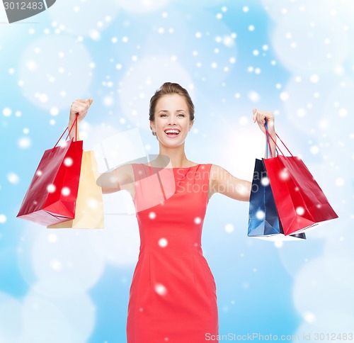 Image of smiling elegant woman in dress with shopping bags