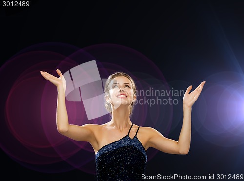 Image of smiling woman raising hands and looking up