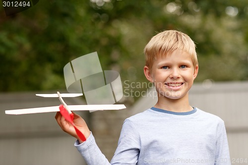 Image of smiling little boy holding a wooden airplane model