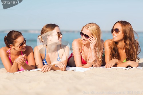 Image of group of smiling women in sunglasses on beach