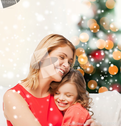 Image of happy mother and daughter hugging at home