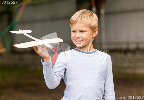 Image of smiling little boy holding a wooden airplane model