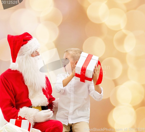 Image of smiling little boy with santa claus and gifts