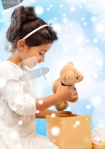 Image of smiling little girl with gift box and teddy bear