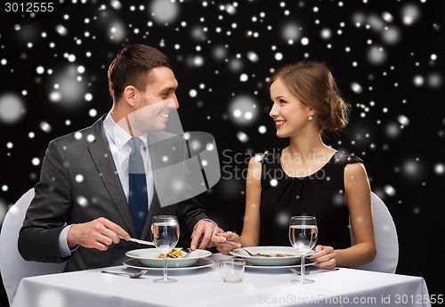 Image of smiling couple eating main course at restaurant