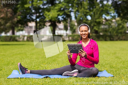 Image of smiling woman with tablet pc outdoors