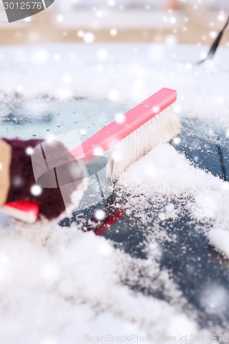 Image of closeup of woman cleaning snow from car