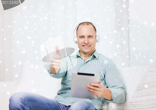 Image of smiling man with tablet pc sitting on couch