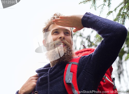 Image of smiling man with beard and backpack hiking