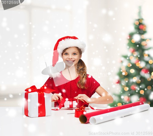 Image of smiling girl in santa helper hat with gift box