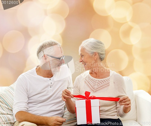Image of happy senior couple with gift box at home