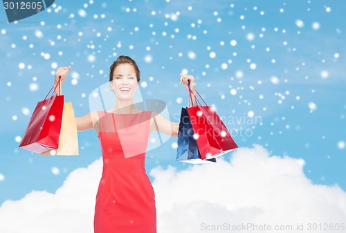 Image of smiling elegant woman in dress with shopping bags