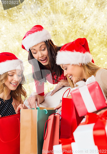 Image of smiling young women in santa hats with gifts