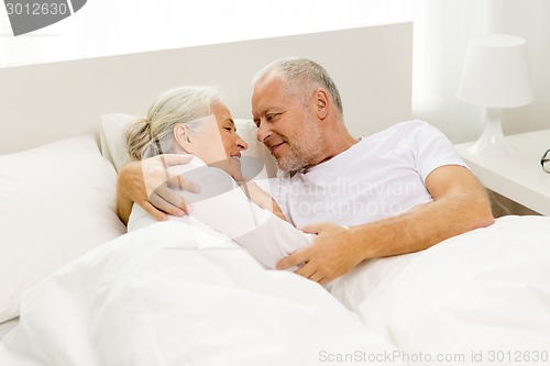 Image of happy senior coupler lying in bad at home